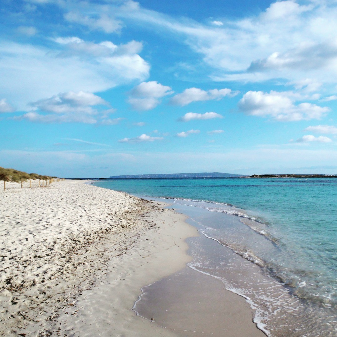 Biała piaszczysta plaża i turkusowa płytka woda przy wyspie Espalmador obok Formentery